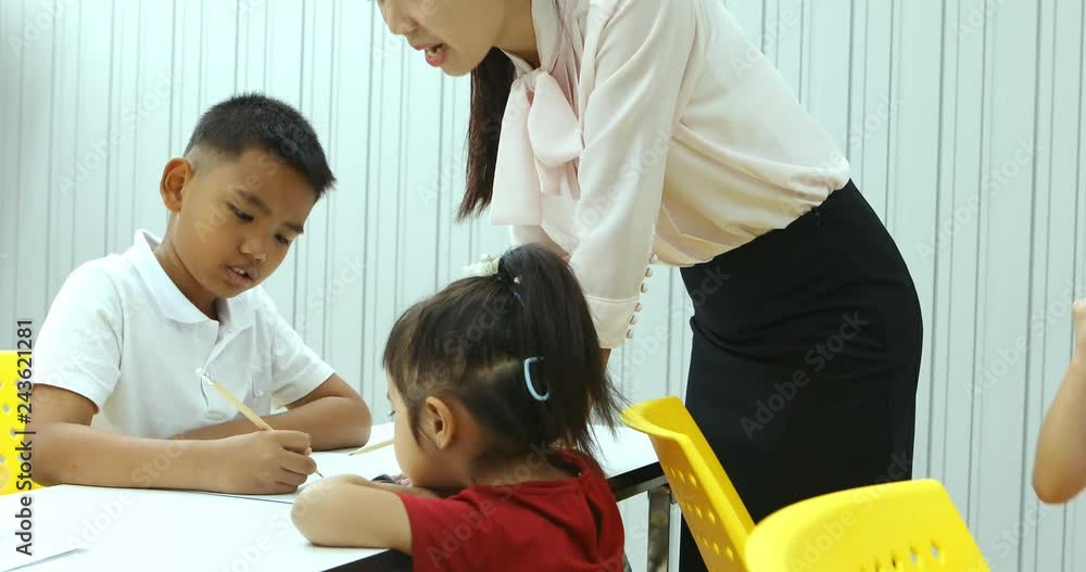 Asian teacher checking students exercise in class, concept for teacher checking students's exercise. Asian teacher checking students exercise in class, concept for teacher checking students's exercise.