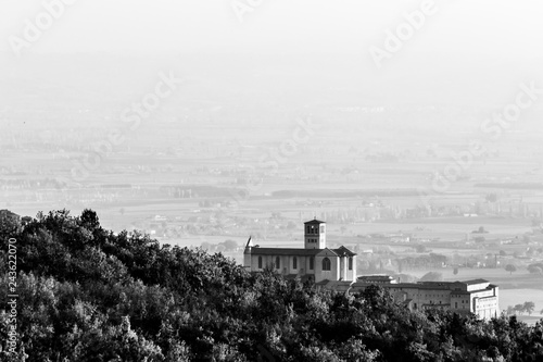 Beautiful view of Assisi town (Umbria) and St.Francis chirch in autumn from an unusual place, behind an hill with trees