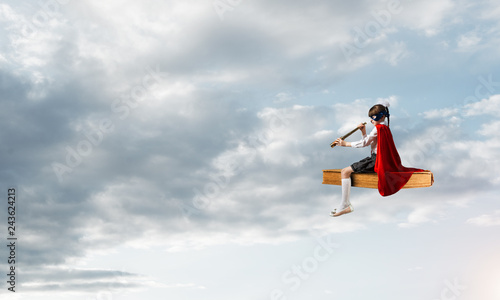 Girl power concept with cute kid guardian against cloudscape background © adam121