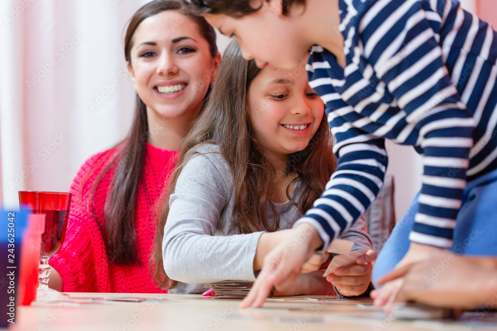 Smiling mother in front of sibling playing cards at home Smiling mother in front of sibling playing cards at home