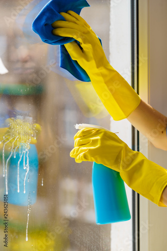 Gloved hand cleaning window rag and spray