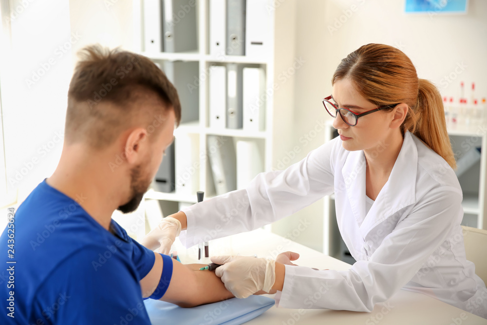 Obraz premium Female doctor drawing a blood sample of male patient in clinic