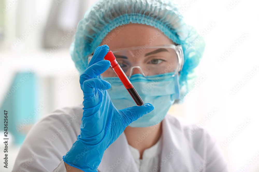 Naklejka premium Medical professional examining blood sample in test tube for laboratory analysis and disease diagnosis, the focus is on scientific investigation and medical testing procedures