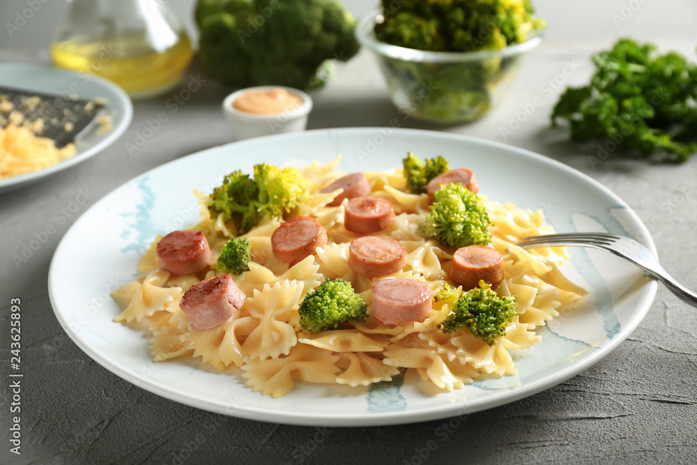 Plate with delicious pasta and sausage on grey table Plate with delicious pasta and sausage on grey table