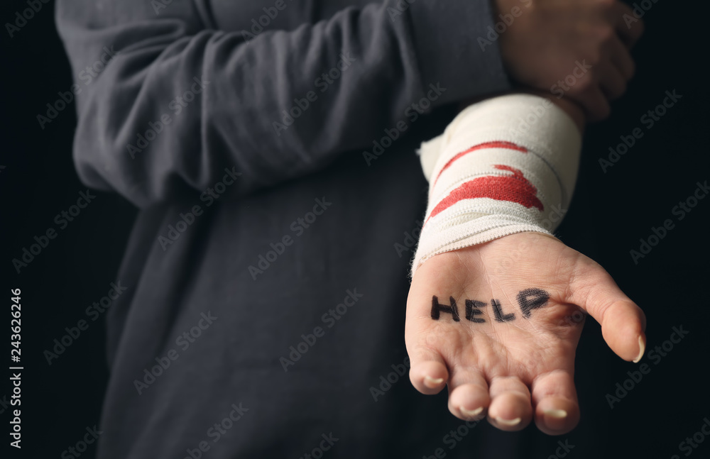 Woman with bloodstained bandage and word help written on her palm. Suicide awareness concept