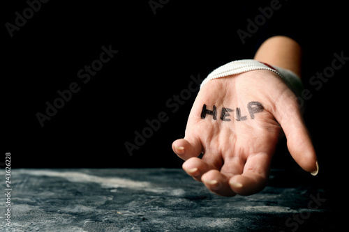 Woman with wrist bandage and word help written on her palm. Suicide awareness concept photo