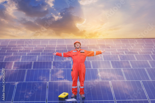 Electrical and instrument technician has relax by open arms after maintenance electric system at solar panel field with sunsut background.
