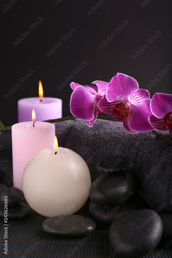 Beautiful spa composition with candles, stones and bath towel on dark table
