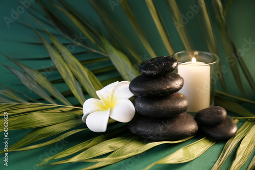 Beautiful spa composition with candle  stones and tropical flower on color background