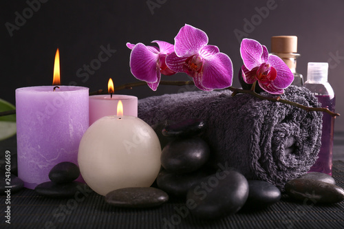 Beautiful spa composition with candles  stones and bath towel on dark table