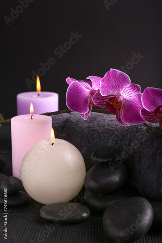 Beautiful spa composition with candles  stones and bath towel on dark table