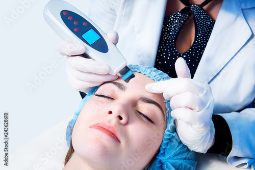 Procedure of ultrasonic cleaning of face. Medical treatment and skin care.The doctor-cosmetologist makes the apparatus a procedure of ultrasound cleaning of the facial skinon a white background. photo