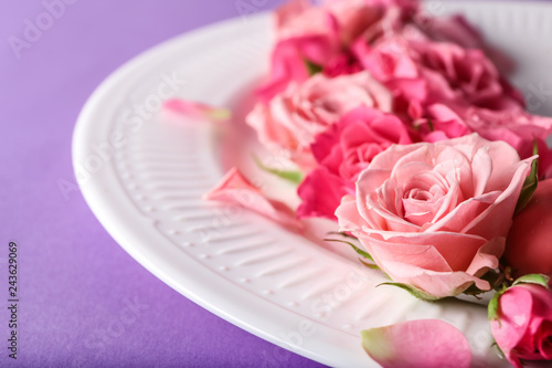 Plate with beautiful flowers on color background  closeup