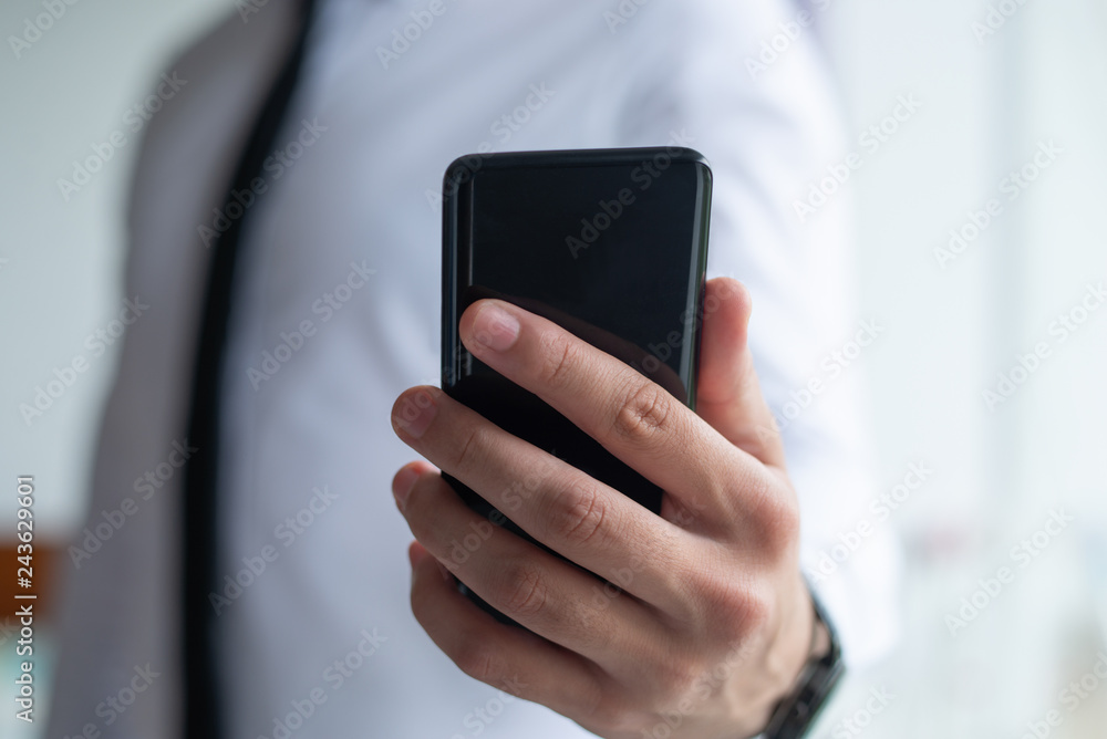 Closeup of business man holding smart phone. Entrepreneur using digital device. Communication and technology concept. Cropped front view. Closeup of business man holding smart phone. Entrepreneur using digital device. Communication and technology concept. Cropped front view.