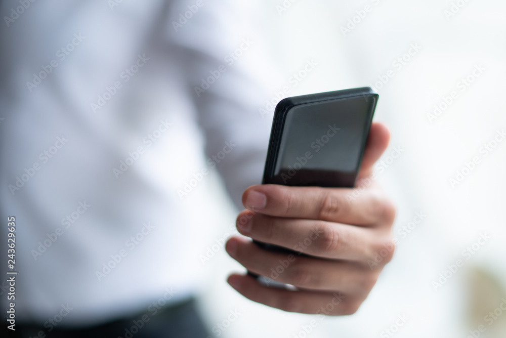 Closeup of business man holding smartphone. Person using holding smartphone. Communication concept. Cropped view. Closeup of business man holding smartphone. Person using holding smartphone. Communication concept. Cropped view.