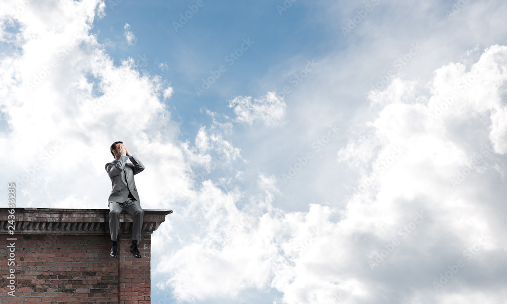 Young man on building edge do not want to see anything