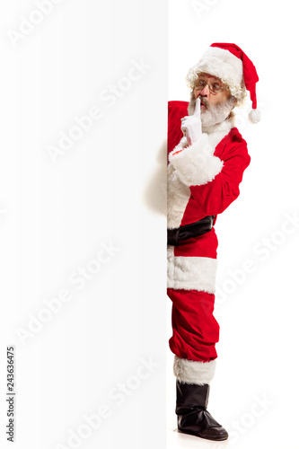 Happy surprised Santa Claus pointing on blank advertisement banner background with copy space. Smiling senior man showing at white blank of empty poster