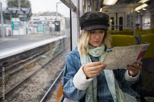 Woman tourist sitting in a train and looking at the route map. Young woman looking at city transport plan
