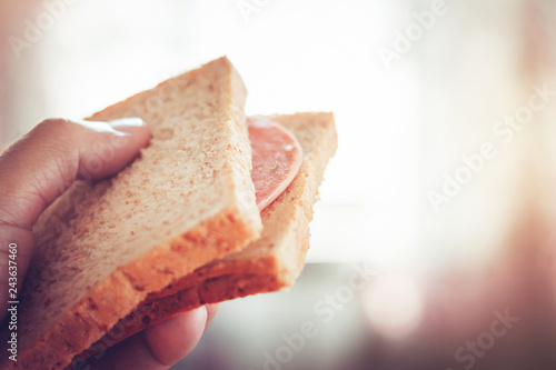 Close up of hands holding bread with ham. select focus blur background. concept make minimal and easy food. vintage color tone