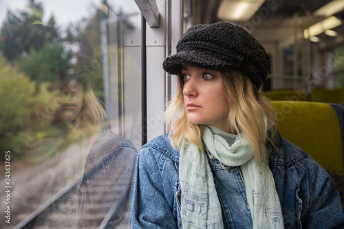 Young woman traveler looking through window in train