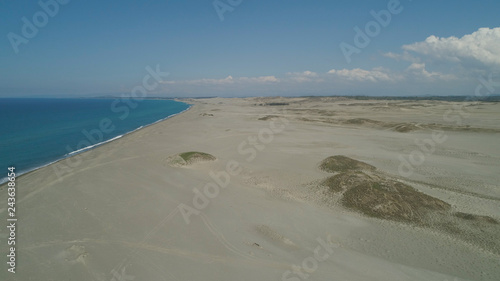 Fototapeta Naklejka Na Ścianę i Meble -  Aerial view of beautiful lonely beach and Paoay sand dune. Philippines, Luzon. Sand dunes near to the sea with sky. Ilocos Norte.
