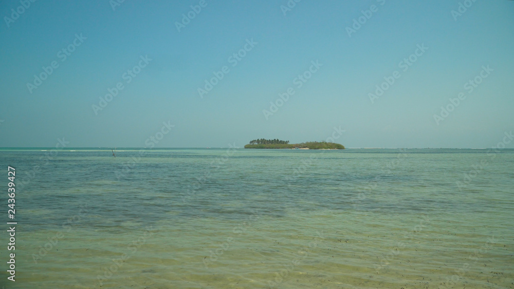 Tropical island with white sandy beach, palm trees in blue lagoon. Tanduyong island with turquoise water. Seascape, ocean and beautiful beach. Philippines, Anda, Pangasinan. Travel concept.