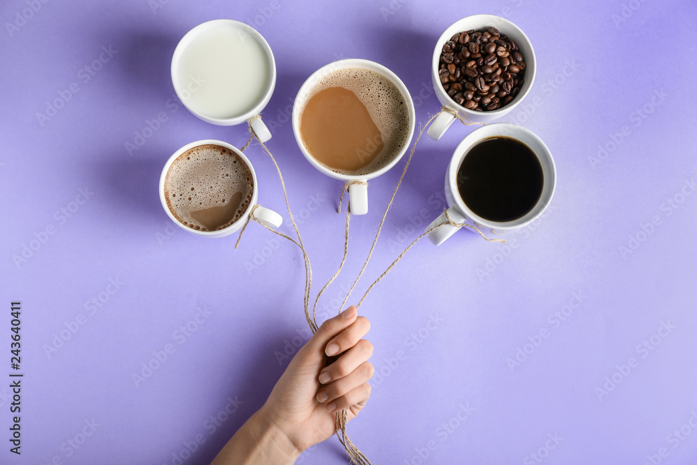 Creative composition with cups of coffee on color background