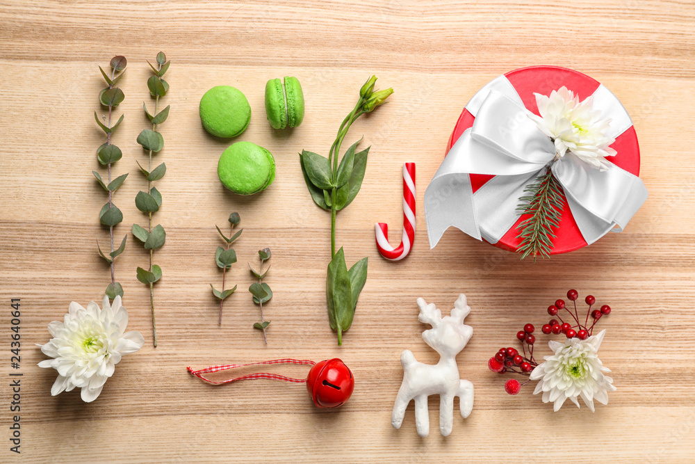 Fototapeta premium Flat lay composition with gift box, flowers and Christmas decor on wooden background