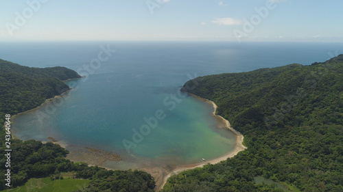 Aerial view of tropical beach in bay with turquoise water. Siwangag Cove. Coast of tropical island Palau with mountains covered rainforest. Santa Ana, province of Cagayan, Philippines.