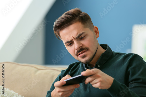 Young man playing game on smartphone at home