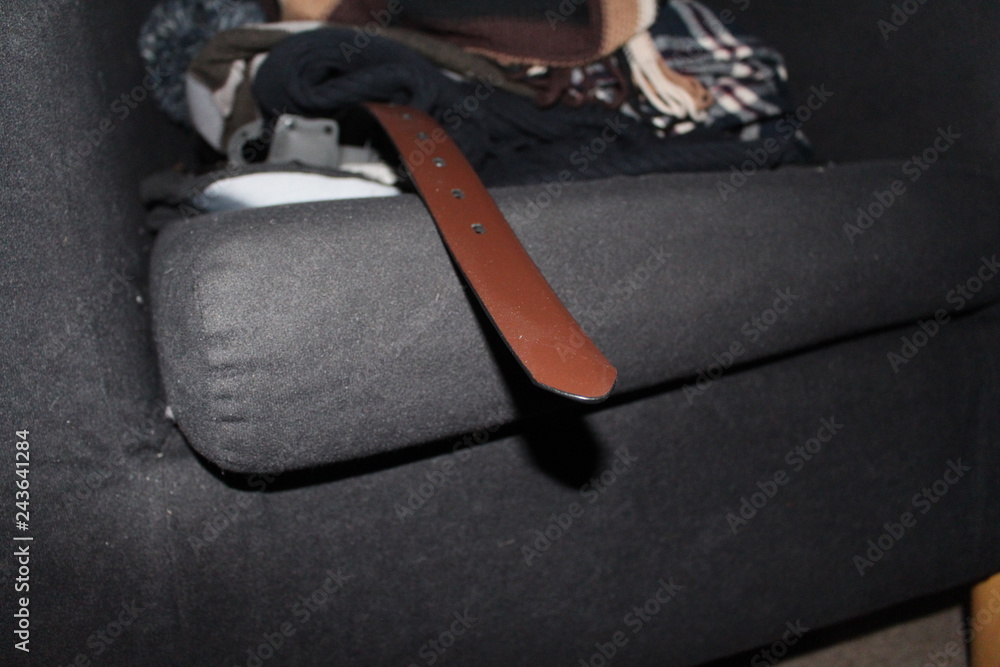 brown belt tip on sofa with various clothing brown belt tip on sofa with various clothing