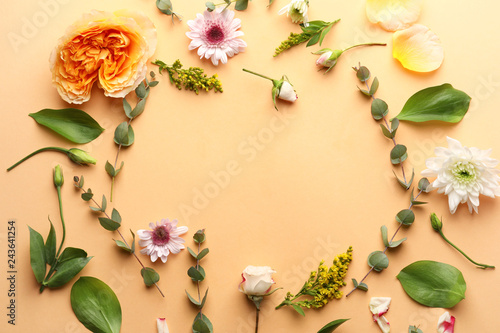 Frame made of different flowers and leaves on color background