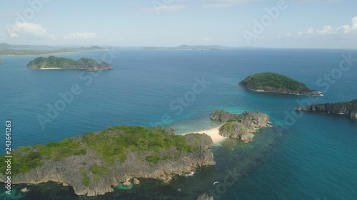 Aerial view island with sand beach and turquoise water in blue lagoon among coral reefs, Caramoan Islands, Philippines. Landscape with sea, tropical beach.