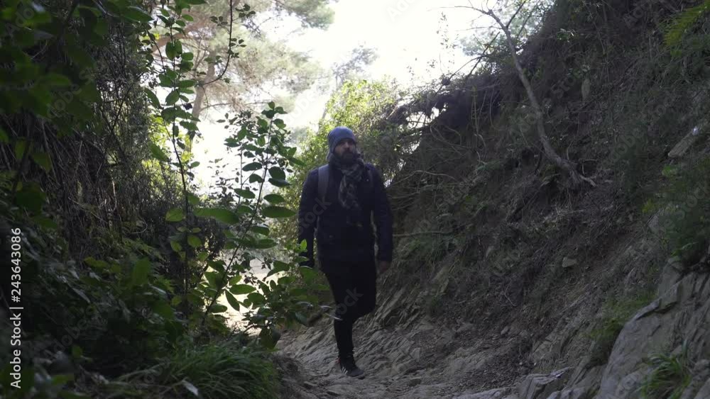 The guy climbs up the steep narrow rocky road in forest The guy climbs up the steep narrow rocky road in forest