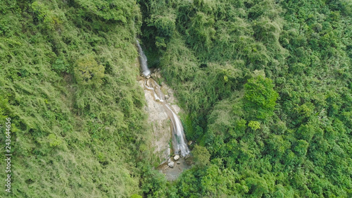 Aerial view of waterfall in the mountains of Filipino cordillera. Waterfall in the mountains. Waterfall flowing on the slopes of mountains covered with tropical vegetation. Philippines, Luzon
