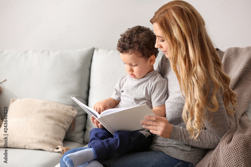 Young mother with cute little son reading book at home