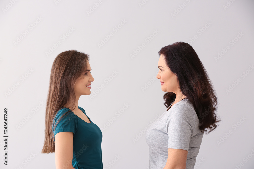 Portrait of young woman with her mother on light background Portrait of young woman with her mother on light background