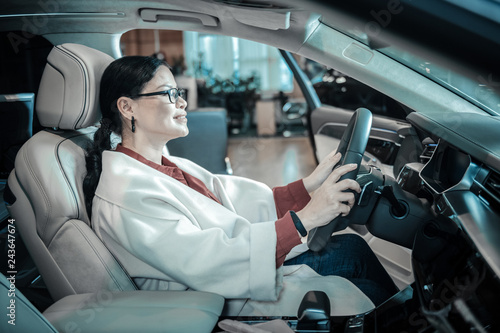 Businesswoman wearing beige coat sitting in car before buying it