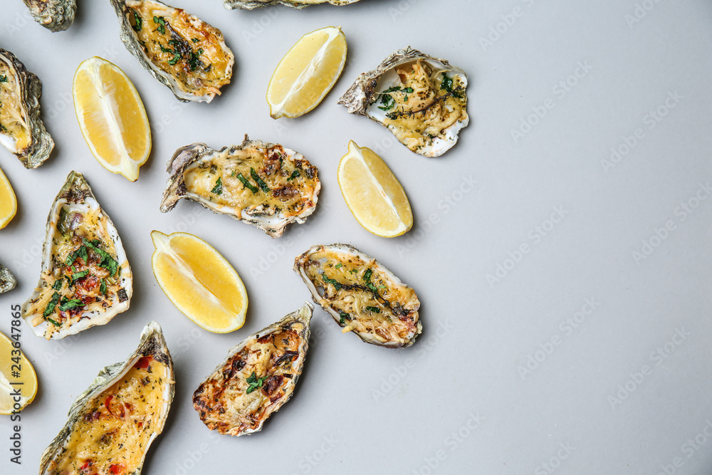 Tasty baked oysters with lemon on grey background Tasty baked oysters with lemon on grey background