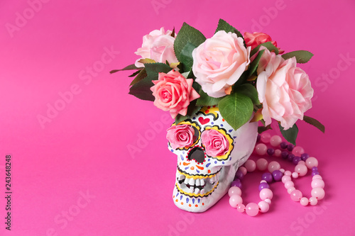 Fototapeta Naklejka Na Ścianę i Meble -  Painted human skull with flowers and beads for Mexico's Day of the Dead on color background