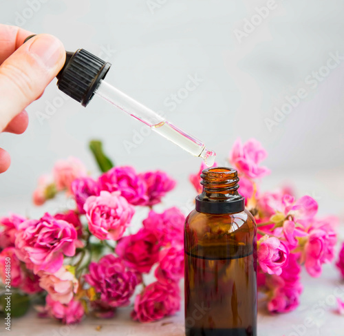 Rose oil bottle and dropper, aromatherapy and spa with roses flowers, spa setting