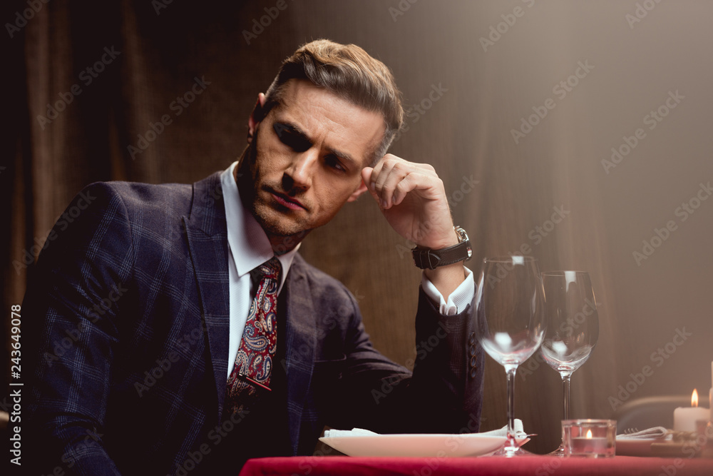 handsome pensive man sitting at table and waiting for someone in restaurant handsome pensive man sitting at table and waiting for someone in restaurant