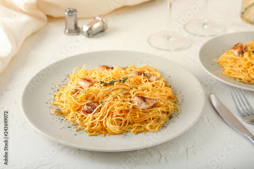 Plate with tasty pasta and chicken on table