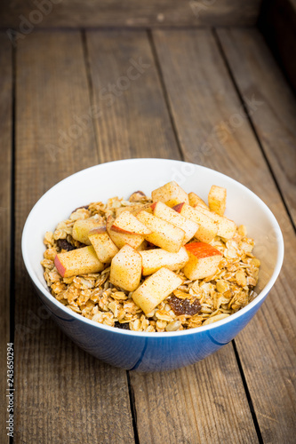 Healthy and tasty breakfast with muesli, apples, nuts and cinnamon. Selective focus.