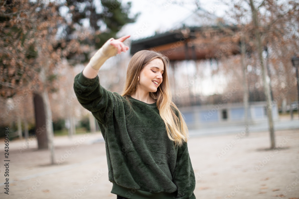 Happy young woman jumping and enjoying with injured arm in the park Happy young woman jumping and enjoying with injured arm in the park