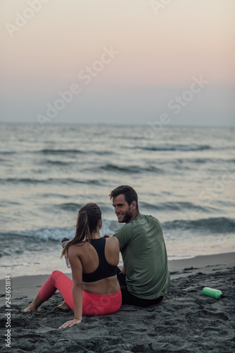 Sportswoman and sportsman Resting on Sandy Beach