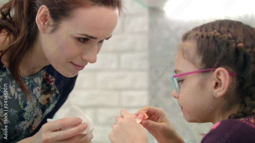 Mom wipe face daugther. Girl eating citrus with mom. Morning healthy food Mom wipe face daugther. Girl eating citrus with mom. Morning healthy food