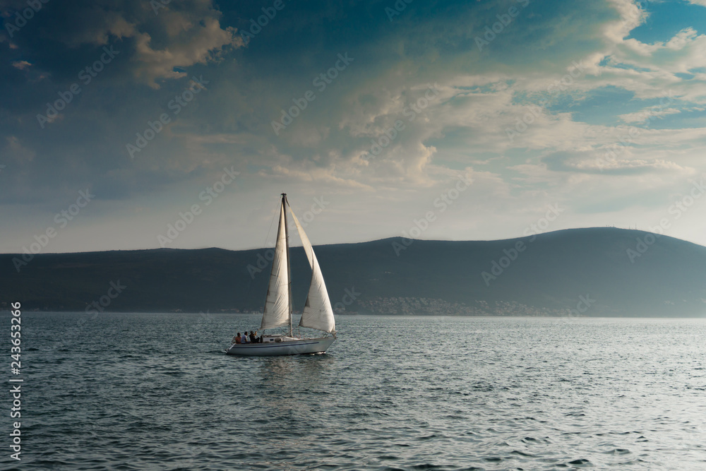 Boat on the blue sea with clouds and mountains on the background