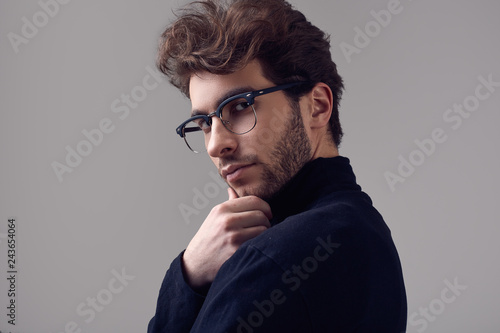 Handsome elegant man with curly hair wearing black turtleneck and glasses