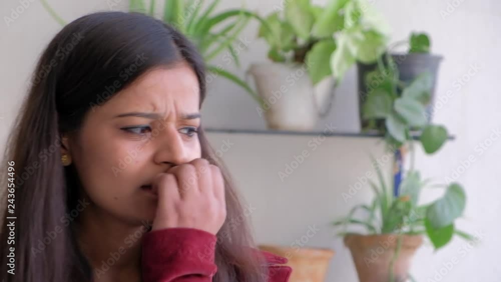 Portrait of a woman looking concerned and worried and looks away and starts to bit her finger nails Portrait of a woman looking concerned and worried and looks away and starts to bit her finger nails